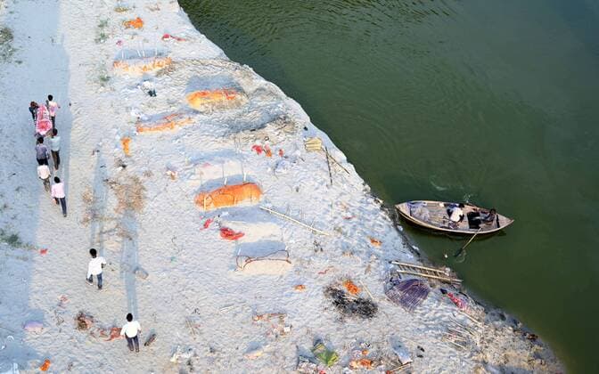 News Bilder des Tages May 16, 2021, Prayagraj, Uttar Pradesh, India: Family members and relatives carrying dead body as they walk past bodies of Deceased buried in the banks of river Ganges at Phaphamau Ghat in Prayagraj, India, Sunday, May 16, 2021. Police are reaching out to villagers in northern India to investigate the recovery of bodies buried in shallow sand graves or washing up on the Ganges River banks, prompting speculation on social media that they were the remains of COVID-19 victims. Prayagraj India - ZUMAv115 20210516_zap_v115_030 Copyright: xPrabhatxKumarxVermax