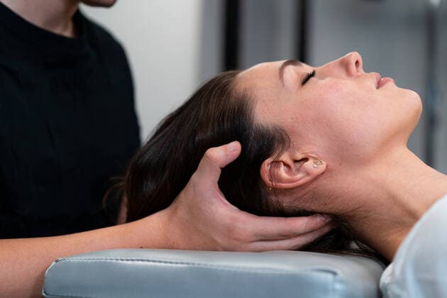 Side view of male physical therapist massaging neck of woman with closed eyes in hospital, Model released Copyright: xEnriquexEspinosax MR