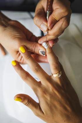 From above of crop unrecognizable manicurist doing nail art for female client in beauty salon in daylight, Model released Copyright: xFrancescxJuanx MR