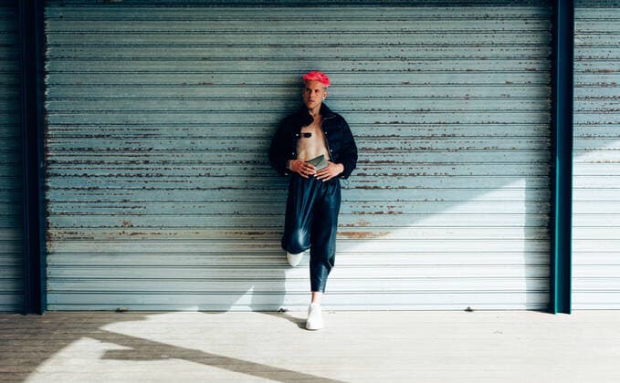 IMAGO Creative: 2021 Favoriten IMAGO Creative: Clickbait, Modetrends Transsexual man in trendy wear with purse and pink hair looking away against weathered wall on sunny day Copyright: xLuisxMarioxHernandezx Model Released