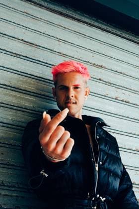 Trendy homosexual man in padded jacket with pink hair showing nail while looking at camera Copyright: xLuisxMarioxHernandezx Model Released