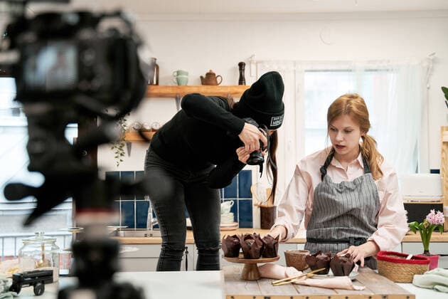 IMAGO Creative: Clickbait, Rezepte und Kochen IMAGO Creative: Kreative Renaissance -- der junge Entrepreneur Unrecognizable woman taking photo of chocolate muffins on digital camera against blogger talking during cooking process in kitchen, Model released Copyright: xSergeyxMironovx MR