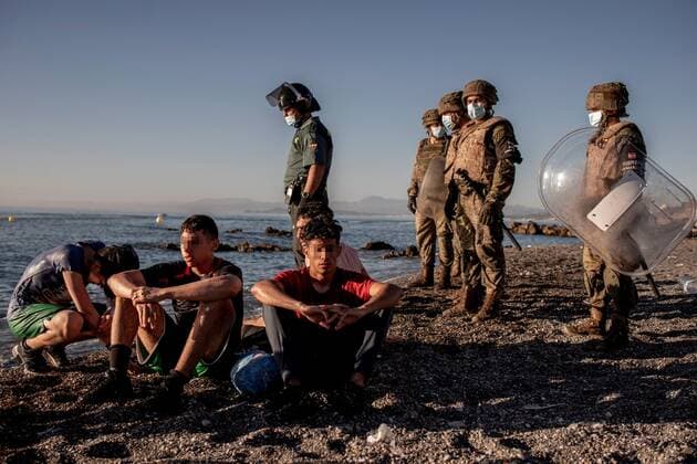 Morocco immigrants rest after reaching El Tarajal beach in the Spanish city of Ceuta, located in northern Africa, as members of the Spanish Army (R) and a member of the Guardia Civil (L) look on, 19 May 2021. Spain s Government considers that the massive arrival of some 8,000 irregular migrants to Ceuta from Morocco since 18 May is an assault on the border caused by the lack of control of the border by Morocco s Governmet and not a migratory crisis. Situation at El Tarajal beach in the Spanish city of Ceuta !ACHTUNG: NUR REDAKTIONELLE NUTZUNG!  Copyright: xBraisxLorenzox GRAF1057 20210519-637570249347369674