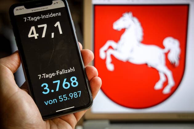 Coronavirus in Deutschland - Covid-19-Dashboard des Robert Koch-Institut DEU, Deutschland, Niedersachsen, 21.05.2021: Die 7-Tage-Inzidenz für das Bundesland (Fälle letzte 7 Tage 100.000 EW) wird auf einem iPhone angezeigt, im Hintergrund das Landeswappen