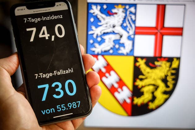 Coronavirus in Deutschland - Covid-19-Dashboard des Robert Koch-Institut DEU, Deutschland, Saarland, 21.05.2021: Die 7-Tage-Inzidenz für das Bundesland (Fälle letzte 7 Tage 100.000 EW) wird auf einem iPhone angezeigt, im Hintergrund das Landeswappen