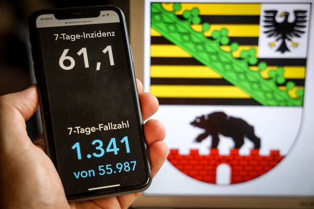Coronavirus in Deutschland - Covid-19-Dashboard des Robert Koch-Institut DEU, Deutschland, Sachsen-Anhalt, 21.05.2021: Die 7-Tage-Inzidenz für das Bundesland (Fälle letzte 7 Tage 100.000 EW) wird auf einem iPhone angezeigt, im Hintergrund das Landeswappen