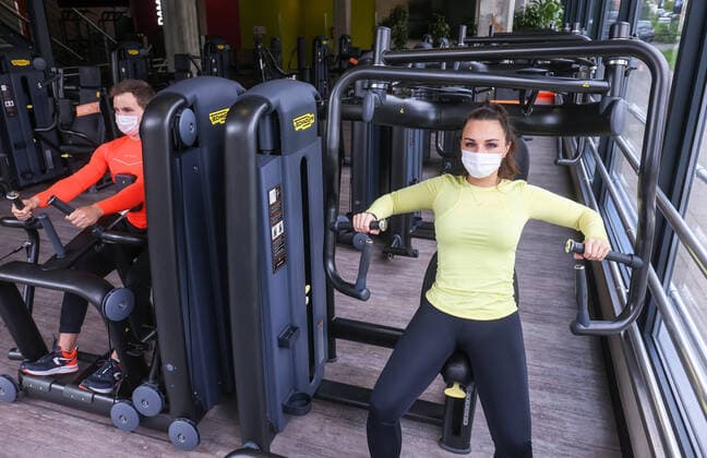 Essen, Nordrhein-Westfalen, Deutschland - Fitnesstraining in Zeiten der Corona Pandemie, Veronika und John nach dem langen Lockdown bei ihrer ersten Trainingseinheit mit Maske im FitX Fitnessstudio, die Stadt Essen und FitX setzen mit wissenschaftlicher Unterstuetzung des Universitaetsklinikums Essen ein Modellprojekt zum sicheren Trainingsbetrieb im Fitnessstudio um, mit innovativer Steuerung der Lueftungsanlagen und Umsetzung der Abstands-, Hygiene- und Arbeitsschutzmaßnahmen, beim Geraetetraining darf die Maske aber abgenommen werden. Essen Nordrhein-Westfalen Deutschland