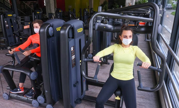 Essen, Nordrhein-Westfalen, Deutschland - Fitnesstraining in Zeiten der Corona Pandemie, Veronika und John nach dem langen Lockdown bei ihrer ersten Trainingseinheit mit Maske im FitX Fitnessstudio, die Stadt Essen und FitX setzen mit wissenschaftlicher Unterstuetzung des Universitaetsklinikums Essen ein Modellprojekt zum sicheren Trainingsbetrieb im Fitnessstudio um, mit innovativer Steuerung der Lueftungsanlagen und Umsetzung der Abstands-, Hygiene- und Arbeitsschutzmaßnahmen, beim Geraetetraining darf die Maske aber abgenommen werden. Essen Nordrhein-Westfalen Deutschland