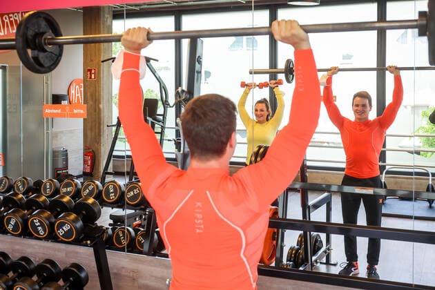 Essen, Nordrhein-Westfalen, Deutschland - Fitnesstraining in Zeiten der Corona Pandemie, Veronika und John freuen sich nach dem langen Lockdown bei ihrer ersten Trainingseinheit im FitX Fitnessstudio, die Stadt Essen und FitX setzen mit wissenschaftlicher Unterstuetzung des Universitaetsklinikums Essen ein Modellprojekt zum sicheren Trainingsbetrieb im Fitnessstudio um, mit innovativer Steuerung der Lueftungsanlagen und Umsetzung der Abstands-, Hygiene- und Arbeitsschutzmaßnahmen, beim Geraetetraining darf die Maske abgenommen werden. Essen Nordrhein-Westfalen Deutschland