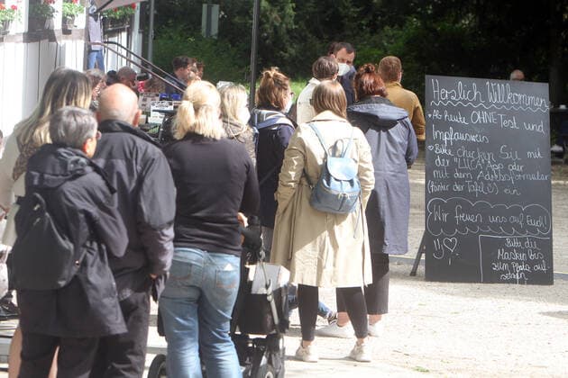Eine lange Warteschlange von Kunden steht vor dem Außenbereich einer geöffneten Gastätte in Bad Nauheim, Hessen, Deutschland. Der Aufsteller trägt die Aufschrift herzlich willkommen, ab heute ohne Test und Impfausweis. Bitte checken Sie mit der Luca App oder mit dem Adressformular ein.