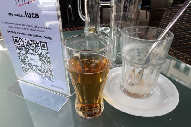 Aufgrund anhaltend niedriger Inzidenzen im Landkreis Wetterau durften gastronomische Betriebe ihren Außenbereich wieder öffnen. Gläser mit Getränken stehen auf dem Tisch eines Restaurant s in der Innenstadt von Bad Nauheim, Hessen, Deutschland. Daneben befindet sich ein Aufsteller mit dem QR Code der Luca App zur Kontaktverfolgung.