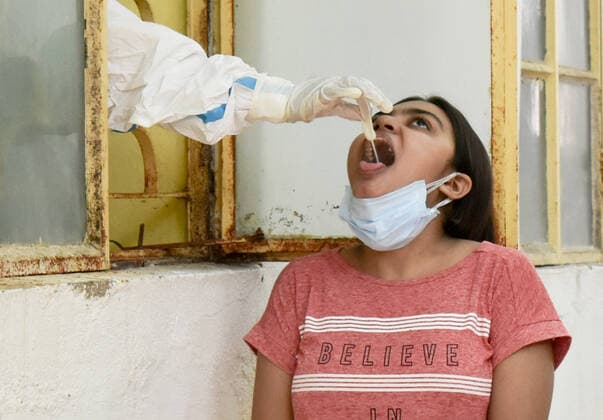India: Covid-19 testing in Kolkata A Healthcare worker collects a swab sample from a woman for Covid-19 testing inside a Government health centre during the Lockdown period in Kolkata. Kolkata West Bengal India Copyright: SudiptaxDas