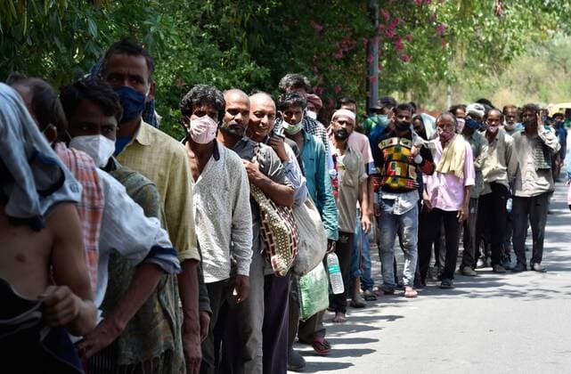 NEW DELHI, INDIA - MAY 21: Daily wage labourers and homeless people line up to collect food during a community feeding session, amid the Covid-19 induced lockdown, near ISBT, on May 21, 2021 in New Delhi, India. (Photo by Ajay Aggarwal Hindustan Times) Daily Life Amid Coronavirus Pandemic In India