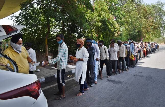 NEW DELHI, INDIA - MAY 21: Daily wage labourers and homeless people line up to collect food during a community feeding session, amid the Covid-19 induced lockdown, near ISBT, on May 21, 2021 in New Delhi, India. (Photo by Ajay Aggarwal Hindustan Times) Daily Life Amid Coronavirus Pandemic In India