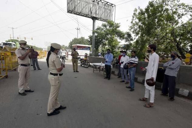 NEW DELHI, INDIA - MAY 23: Delhi police officer offer flowers to people who stepped out of their homes during lockdown and requested them to stay indoor and follow covid guidelines At Geeta colony on May 23, 2021 in New Delhi, India. Police also distributed masks and sanitizers to the violators. Delhi reported 1649 new cases of COVID on May 23.(Photo by Sonu Mehta Hindustan Times) Delhi Police Give Roses To Lockdown Violators