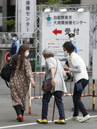 Mass vaccination center in Tokyo A senior citizen (C) walks to a newly opened mass coronavirus vaccination center in Tokyo on May 24, 2021. 