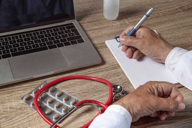 IMAGO Creative: Bildung, Schreiben Doctor working with laptop and writing on paper Barcelona, CT, Spain CR_AULNOK210523F-752828-01 ,model released, Symbolfoto