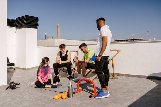 IMAGO Creative: Urban Diversity Full body of positive young multiracial friends training together with various equipment on rooftop against cloudless blue sky Copyright: xJavierxBallesterx Model Released