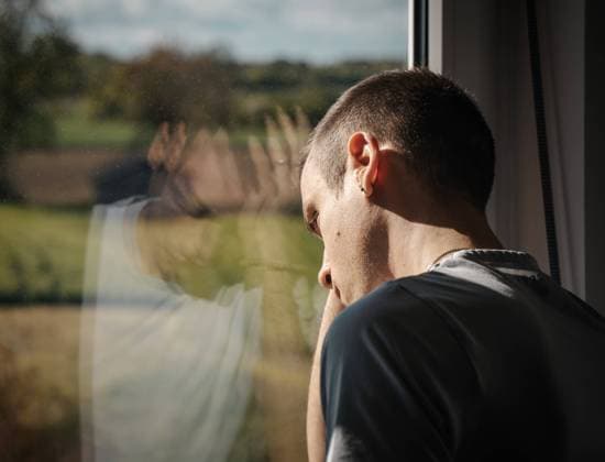 augsburg, bavaria, germany - 25 may 2021: desperate man stands hopelessly at the window
