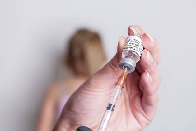 Bamberg, Deutschland 27. Mai 2021: Eine Person zieht mit Hilfe einer Impfspritze eine Impfdosis mit dem mRNA-Impfstoff Comirnaty, BNT162b2, Biontech Pfizer aus einer Ampulle. Im Hintergrund sitzt ein Mädchen im Schulalter. Bayern *** Bamberg, Germany 27 May 2021 A person draws a vaccine dose containing the mRNA vaccine Comirnaty, BNT162b2, Biontech Pfizer from an ampoule using a vaccination syringe A school-aged girl sits in the background Bavaria Copyright: xFotostandx xK.xSchmittx