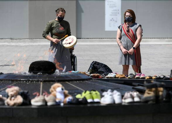 May 30, 2021, Ottawa, on, Canada: Jordyn Hendricks, left, and their sister Marissa, right, drum and sing the Traveling Song at the Centennial Flame on Parliament Hill in Ottawa, where shoes were placed to symbolize the 215 children whose remains were found at the grounds of the former Kamloops Indian Residential School at TkÃ¢â‚¬â ¢emlups te Secwo pemc First Nation in Kamloops, B.C., on Sunday, May 30, 2021, Ottawa Canada  - ZUMAc35_ 20210530_zaf_c35_046 Copyright: xJustinxTangx