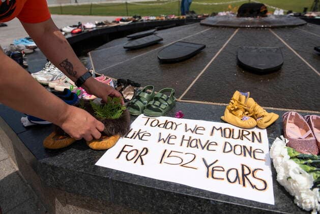 May 30, 2021, Ottawa, on, Canada: Stephanie Gilpin, whose parents, aunts and uncles were sent to residential schools, smooths out the cedar that she placed in a pair of moccasins at the Centennial Flame on Parliament Hill in Ottawa, in memory of the 215 children whose remains were found at the grounds of the former Kamloops Indian Residential School at TkÃ¢â‚¬â ¢emlups te Secwo pemc First Nation in Kamloops, B.C., on Sunday, May 30, 2021, Ottawa Canada  - ZUMAc35_ 20210530_zaf_c35_048 Copyright: xJustinxTangx