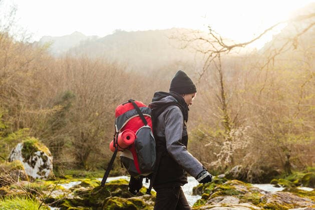 IMAGO Creative: Digitale Welt, Verzicht auf Technologie Side view of explorer with backpack walking on mossy rocks near rapid stream of water flowing among forest with leafless trees, Model released Copyright: xAlbertoxMenendezx MR