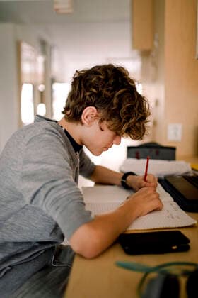 Boy writing in book while doing homework sitting at table Sweden, Stockholm, model released, property released Copyright: xMaskotx , MA86506