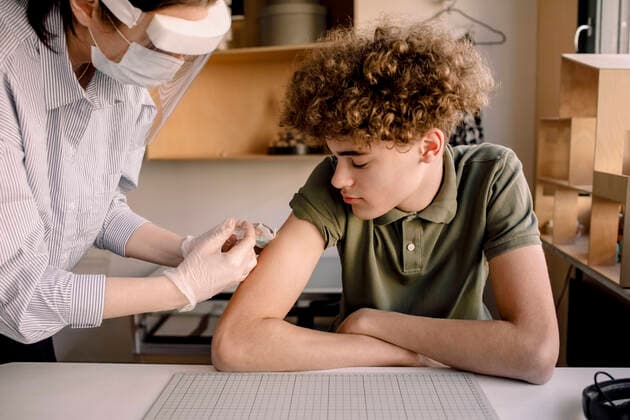 IMAGO Creative: 2022 Aussichten IMAGO Creative: NGO, Rehabilitation und Gesundheitswesen Boy with curly brown hair looking at nurse injecting medicine at home Sweden, Stockholm, model released, property released Copyright: xMaskotx , MA86528
