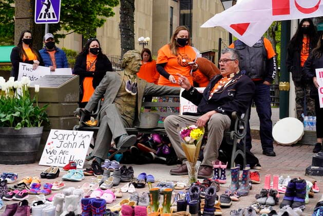 May 31, 2021, CHARLOTTETOWN, PE, Canada: Elder Junior Peter Paul (sitting) points to a Sir John A. MacDonald statue next to 215 pairs of children s shoes placed in remembrance of the bodies discovered at the Kamloops Indian Residential School in British Columbia during a ceremony in Charlottetown, on Monday, May 31, 2021. CHARLOTTETOWN Canada  - ZUMAc35_ 20210531_zaf_c35_017 Copyright: xJohnxMorrisx