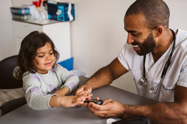 Smiling male pediatrician checking sugar level of girl in medical clinic Sweden, Stockholm, model released, property released Copyright: xMaskotx , MA86768