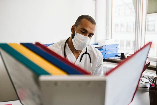 Male healthcare worker reading files at medical clinic during COVID-19 Sweden, Stockholm, model released, property released Copyright: xMaskotx , MA86799