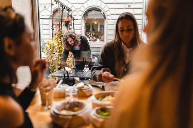 IMAGO Creative: Kollidierende Kulturen IMAGO Creative: Kimawandel - Weihnachten, Weihnachtsessen vegan IMAGO Creative: Kreative Renaissance -- der junge Entrepreneur Multi-ethnic female friends having food in restaurant while waiter cleaning table outside Sweden, Gothenburg, model released, property released Copyright: xMaskotx , MA86803