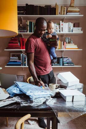 IMAGO Creative: Vaterschaft IMAGO Creative: Bildung, Schreiben IMAGO Creative: 2021 Trends Male entrepreneur writing while carrying baby boy at home Sweden, Stockholm, model released, property released Copyright: xMaskotx , MA86884