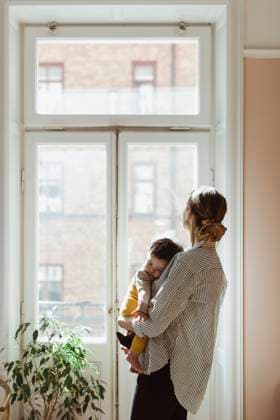 IMAGO Creative: Internationaler Tag der Architektur am 3. Oktober. Thema: Architektur zum Wohlfühlen Mother carrying male toddler while looking through window at home Sweden, Stockholm, model released, property released Copyright: xMaskotx , MA86920