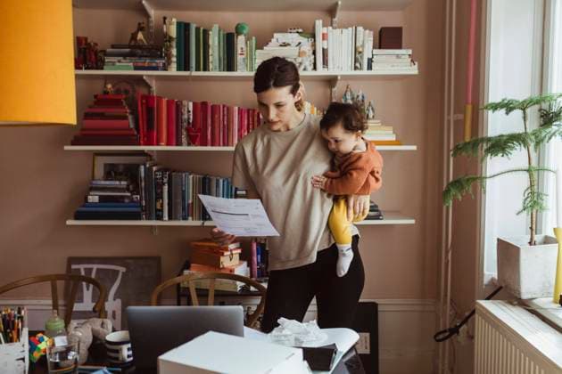 IMAGO Creative, Gesellschaft, Immer mehr Menschen haben Angst vor der Zukunft IMAGO Creative: Mutterschaft IMAGO Creative: Resilienz Female professional reading document while carrying son at home office Sweden, Stockholm, model released, property released Copyright: xMaskotx , MA86941