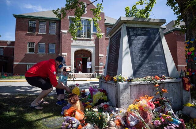 May 31, 2021, Kamloops, BC, Canada: Jaret Hamm and his son John Hamm, 2, place flowers beside a monument outside the former Kamloops Indian Residential School as part of a growing makeshift memorial to honour the 215 children whose remains have been discovered buried near the facility, in Kamloops, B.C., on Monday, May 31, 2021. Kamloops Canada  - ZUMAc35_ 20210531_zaf_c35_072 Copyright: xDarrylxDyckx