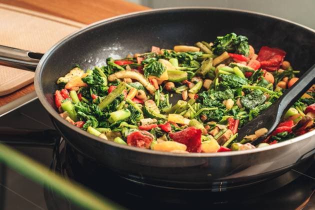 31 may 2021: colorful frozen vegetables are fried in a pan on the electric stove. cooking a vegan dish with frozen vegetables