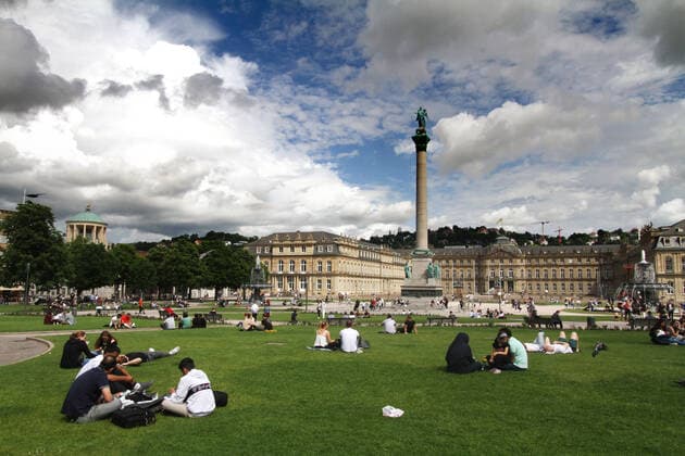 Trotz des wechselhaften Wetters und ständiger Gewittergefahr sitzen viele Personen auf der Grünfläche am Schlossplatz vor dem Schloss in der Innenstadt von Stuttgart, Baden Württemberg, Deutschland
