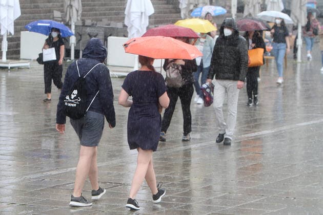 Passanten gehen mit Regenschirmen über den Schlossplatz in der Innenstadt von Stuttgart während eines starken Regenschauers, Baden Württemberg, Deutschland