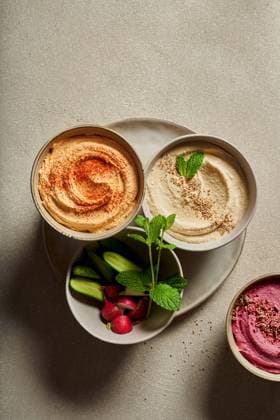 IMAGO Creative, Food, Hummus Top view of bowls with assorted hummus served on table with fresh cucumbers and radish Copyright: xIsxHealthyxPhotox Model Released