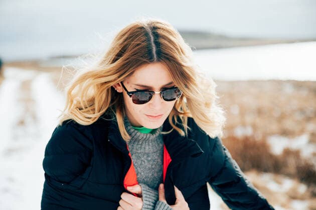 IMAGO Creative: Jahreszeit Winter, Spaziergang Freezing female traveler wrapping in coat and shivering while walking away from van on snowy road against overcast sky and calm water on cold winter day in Iceland, Model released Copyright: xEkaitzxGeriquex MR