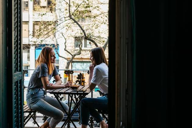 Female friends enjoying drinks while sitting together on balcony model released Symbolfoto property released XLGF01752