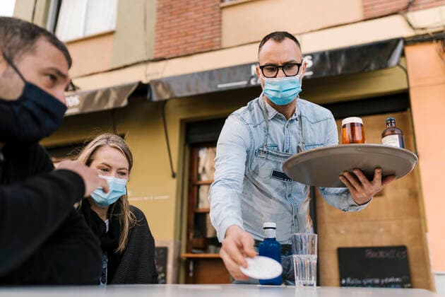 Waiter serving drinks to customers outside a bar during pandemic model released Symbolfoto property released EGAF02301