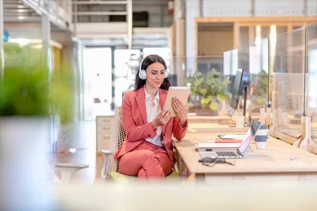 Young businesswoman looking at digital tablet while sitting at desk in coworking office model released Symbolfoto property released EIF00956