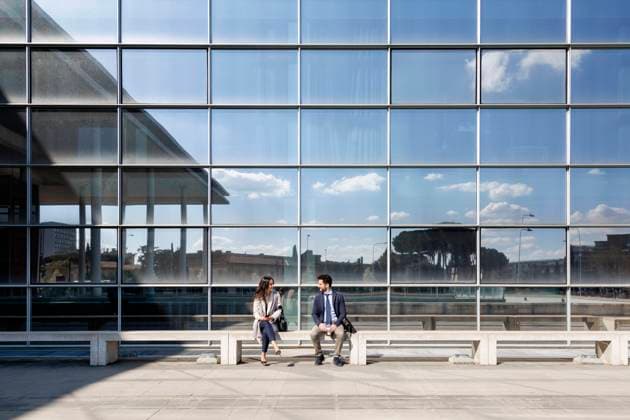 Business couple talking while sitting on bench during sunny day model released Symbolfoto EIF01048