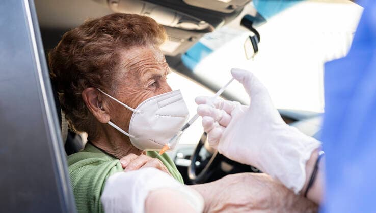 Senior woman getting vaccinated from female doctor in car model released Symbolfoto JCCMF01985