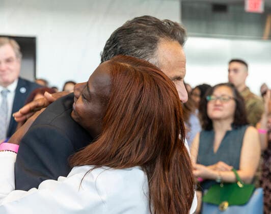 New York: Governor Cuomo Announces COVID-19 Restrictions Lifted Governor Cuomo hugs doctor Sandra Lindsay after announced COVID-19 restrictions lifted as 70% of adult New Yorkers have received first dose of vaccine at One World Trade Center. Governor praised all New Yorkers for doing their parts during pandemic. Governor especially lauded essential workers and presented awards to those who carried New York State through the COVID-19 pandemic. Governor said that mask requirement for unvaccinated individuals and in certain settings (e.g., large-scale indoor event venues, pre-K to grade 12 schools, public transit, homeless shelters, correctional facilities, nursing homes and health care settings per CDC guidance) will stay in place. New York Copyright: LevxRadin
