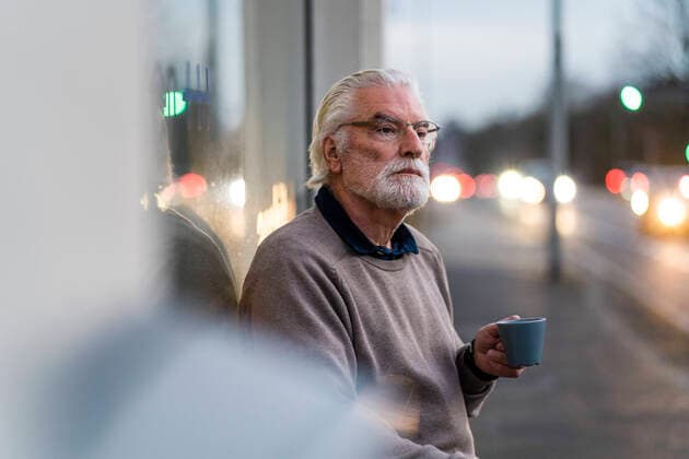 Senior man with eyeglasses holding coffee cup while sitting outside cafe model released Symbolfoto property released MOEF03701