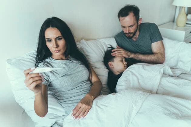 Woman measuring temperature while father taking care of son at home model released Symbolfoto property released OIPF00606